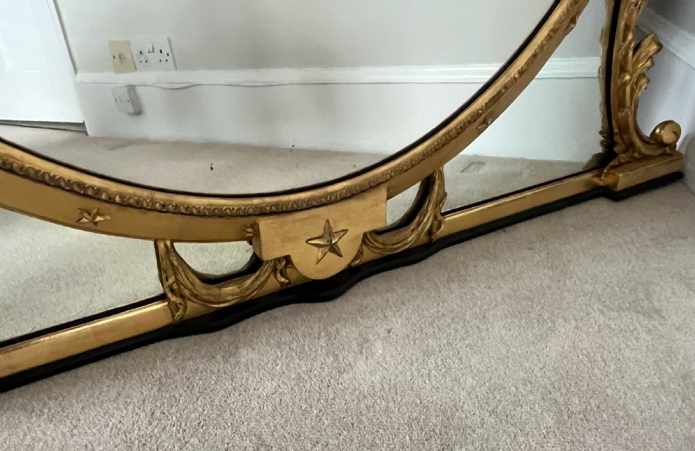 Large Victorian oval overmantel mirror featuring a gilded frame with star motifs, scrollwork base brackets, and an acanthus crest. View III
