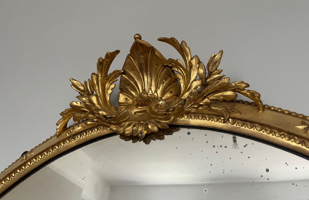 Large Victorian oval overmantel mirror featuring a gilded frame with star motifs, scrollwork base brackets, and an acanthus crest. View VIII