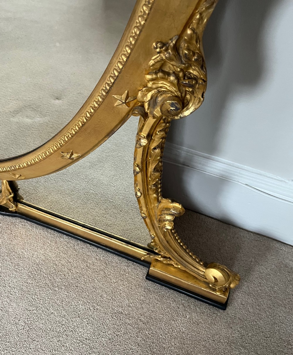 Large Victorian oval overmantel mirror featuring a gilded frame with star motifs, scrollwork base brackets, and an acanthus crest. View IX