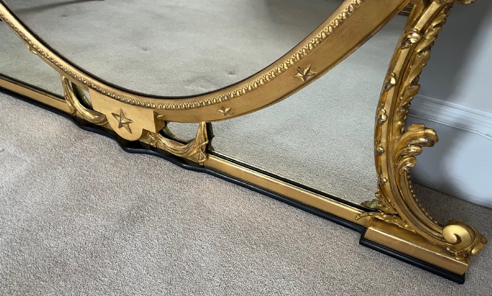 Large Victorian oval overmantel mirror featuring a gilded frame with star motifs, scrollwork base brackets, and an acanthus crest. View X