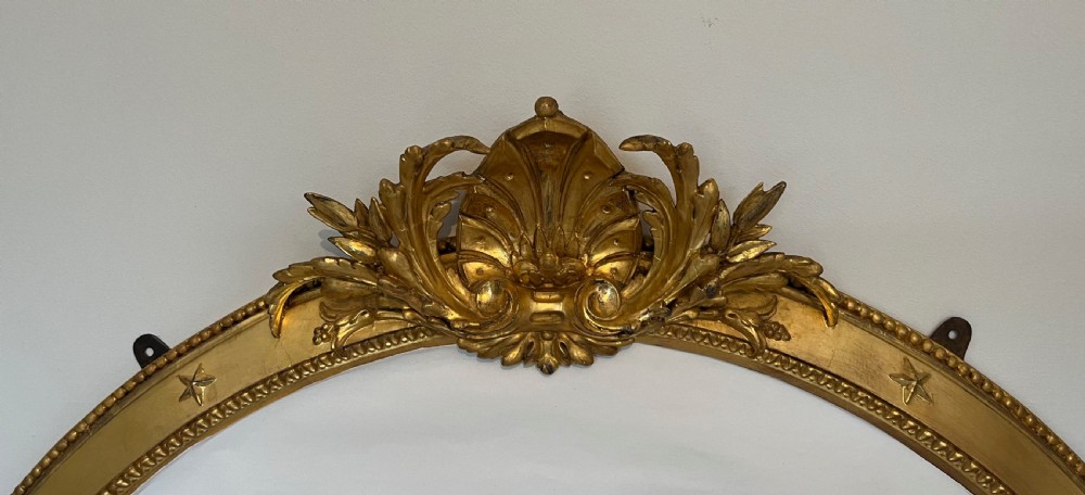 Large Victorian oval overmantel mirror featuring a gilded frame with star motifs, scrollwork base brackets, and an acanthus crest. View XIII