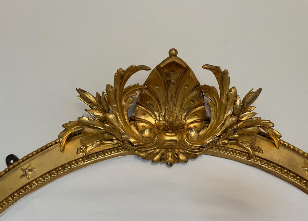 Large Victorian oval overmantel mirror featuring a gilded frame with star motifs, scrollwork base brackets, and an acanthus crest. View XIV