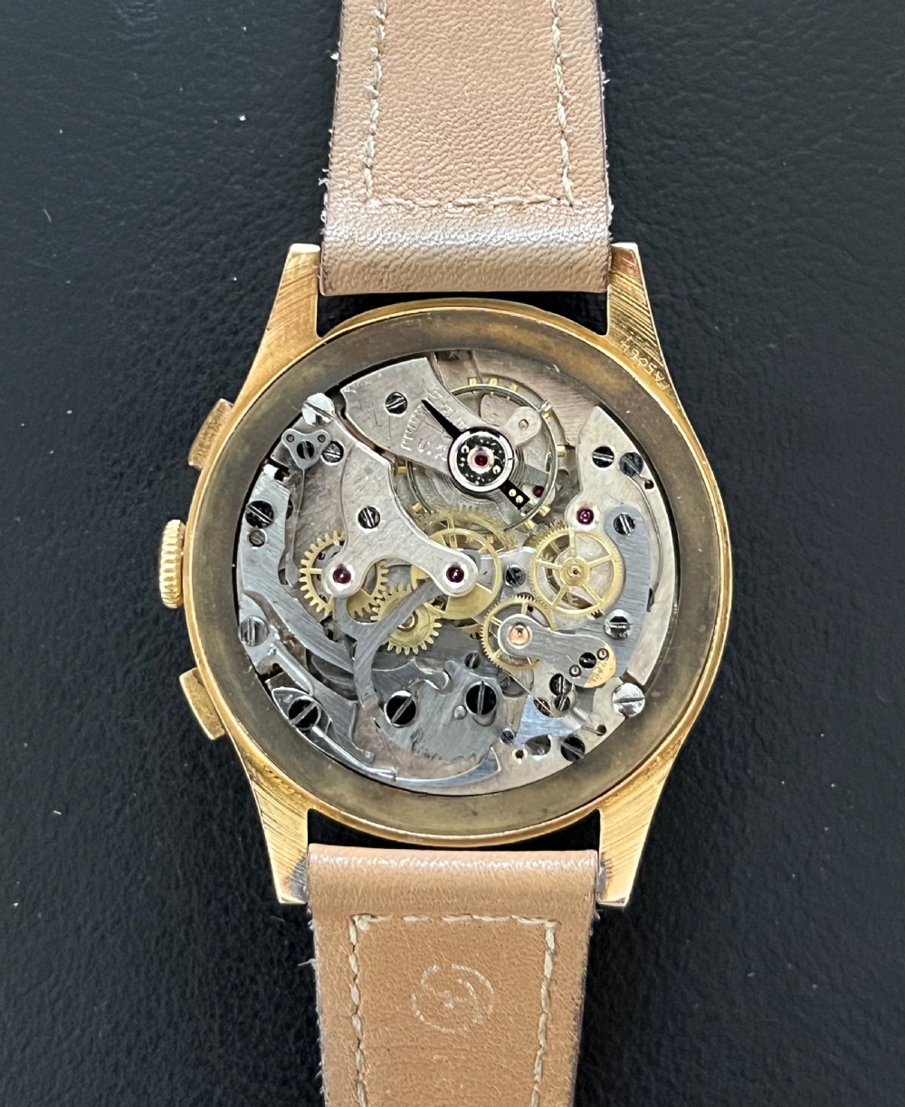 A vintage 18ct gold circular chronograph wristwatch featuring a silvered dial, dual sub-dials, gold hands, and a brown leather strap. View V