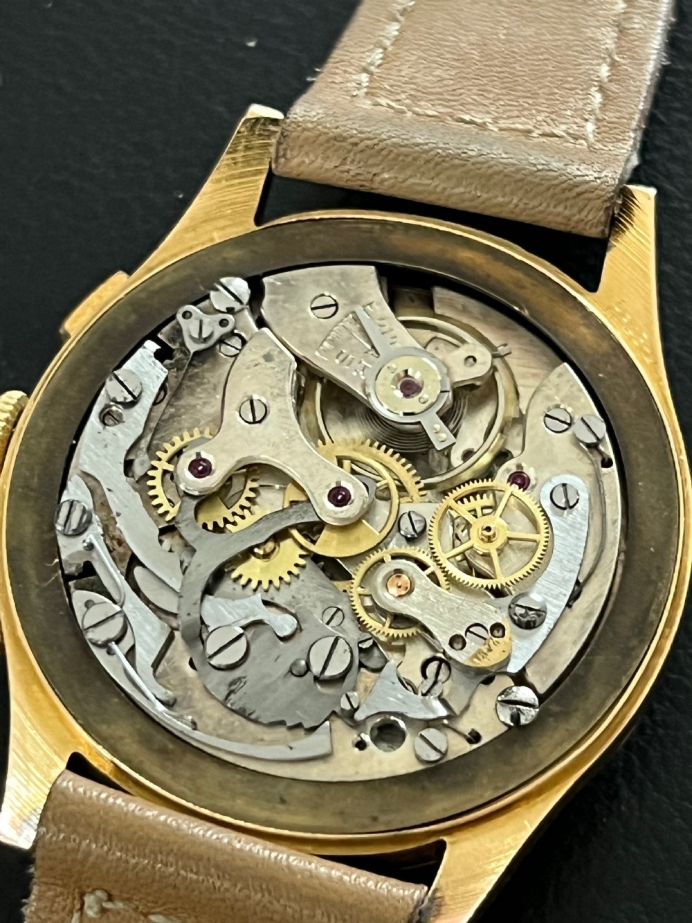 A vintage 18ct gold circular chronograph wristwatch featuring a silvered dial, dual sub-dials, gold hands, and a brown leather strap. View VI