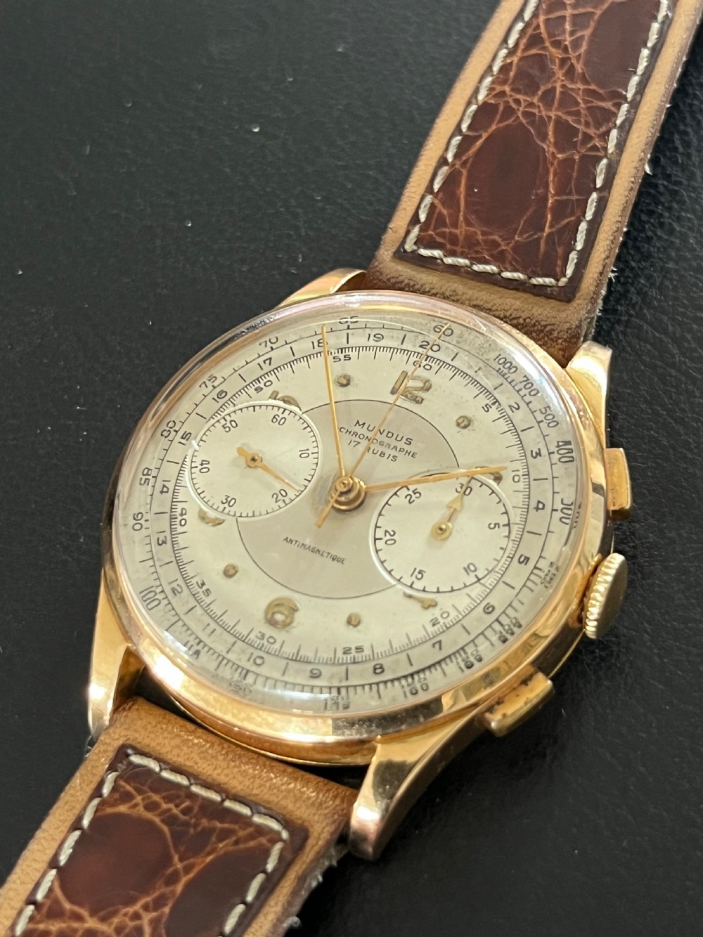 A vintage 18ct gold circular chronograph wristwatch featuring a silvered dial, dual sub-dials, gold hands, and a brown leather strap. View VIII