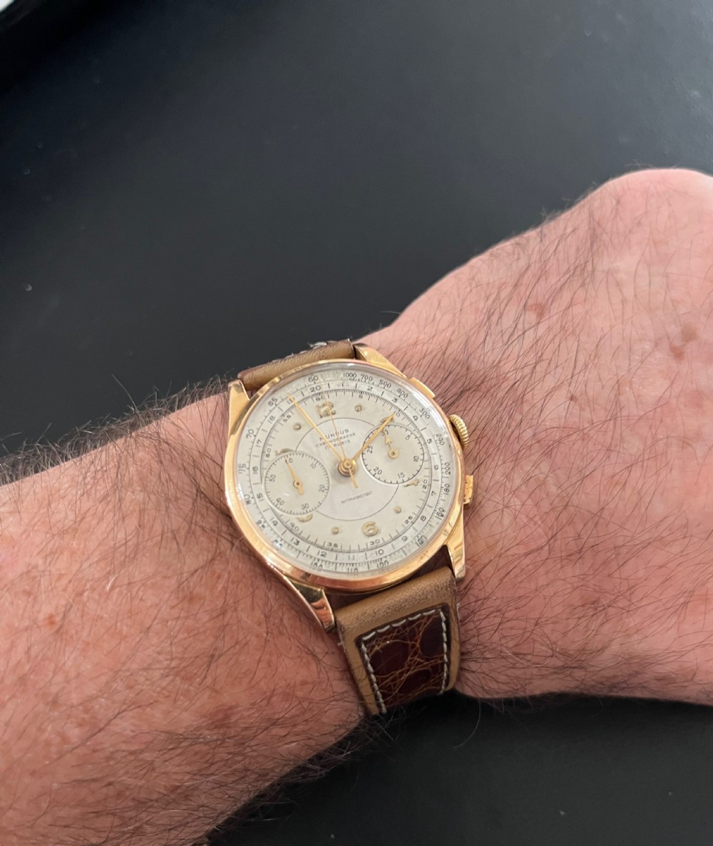 A vintage 18ct gold circular chronograph wristwatch featuring a silvered dial, dual sub-dials, gold hands, and a brown leather strap. View X