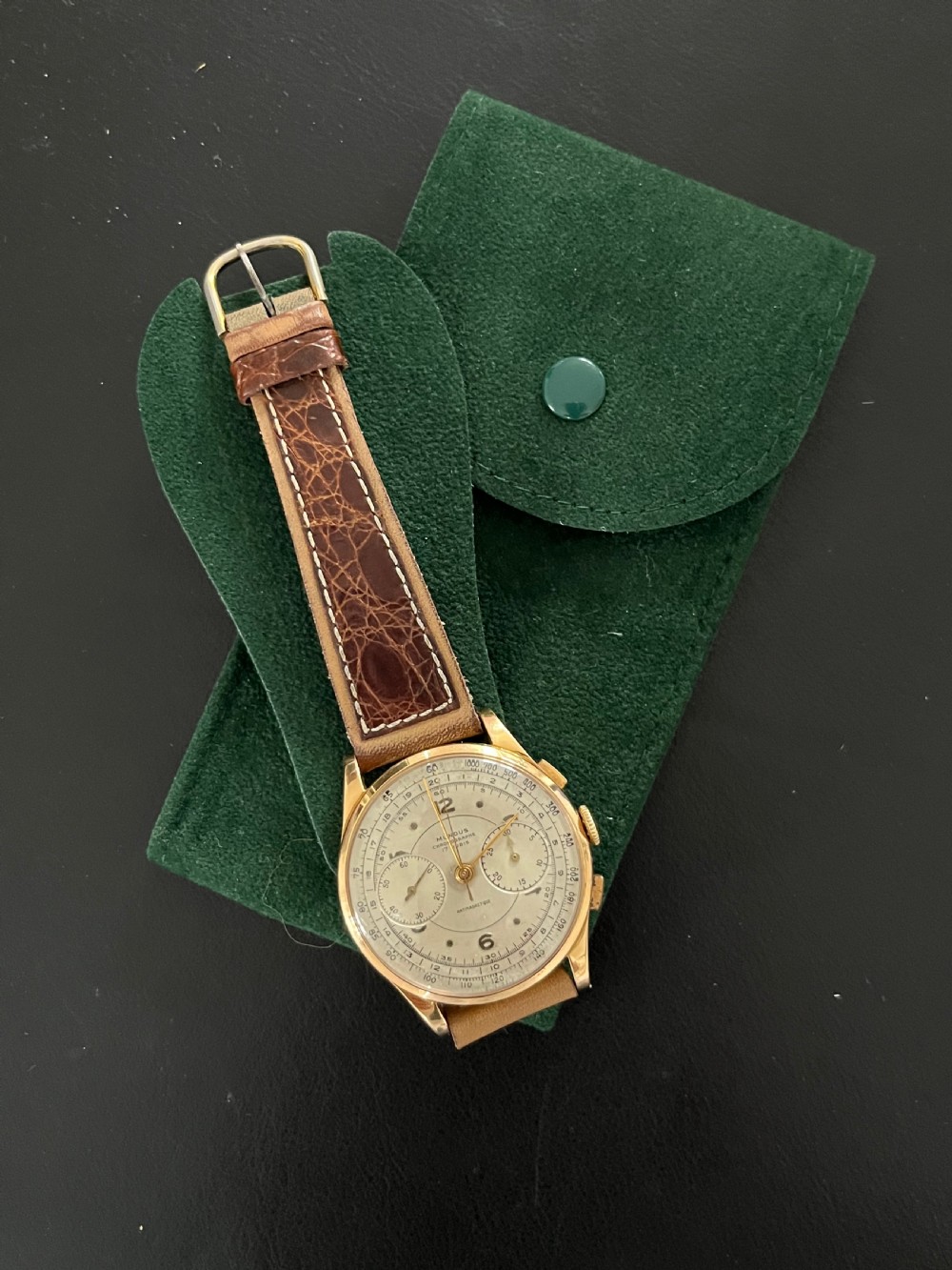 A vintage 18ct gold circular chronograph wristwatch featuring a silvered dial, dual sub-dials, gold hands, and a brown leather strap. View XI