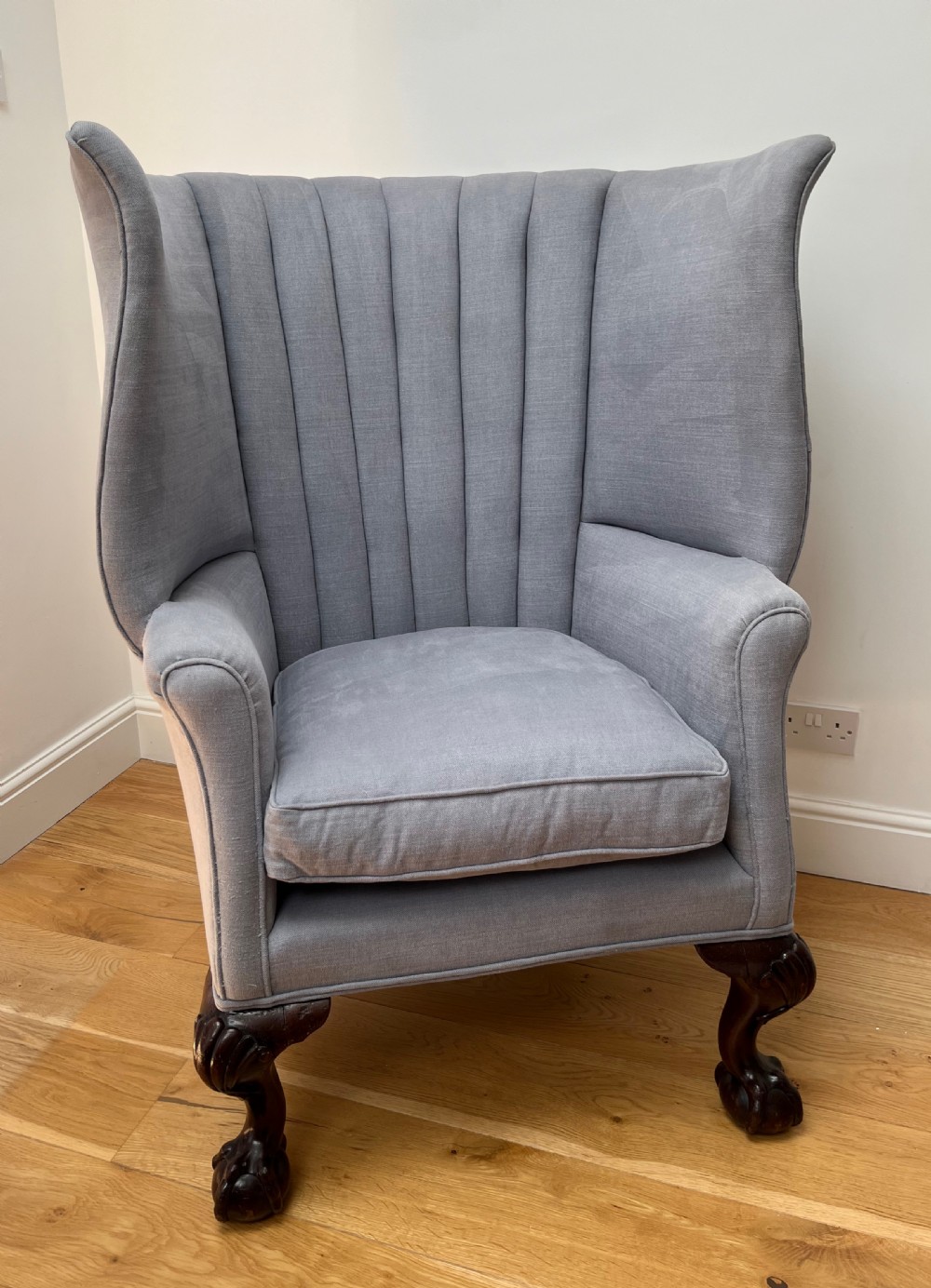 A high-backed Victorian barrel back armchair upholstered in light grey fabric, featuring channel-tufted back detailing and dark carved cabriole legs with ball and claw feet.
