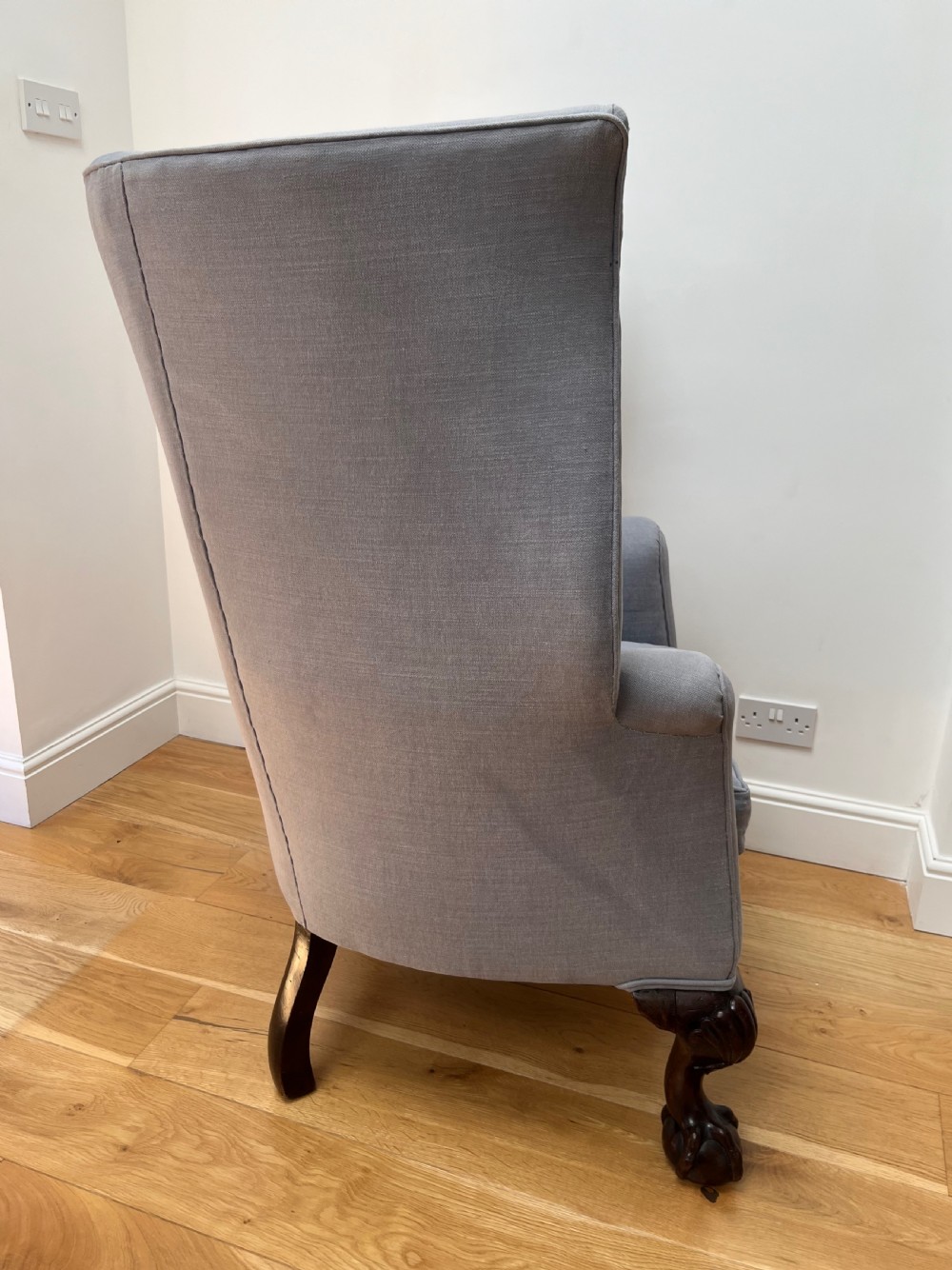 A high-backed Victorian barrel back armchair upholstered in light grey fabric, featuring channel-tufted back detailing and dark carved cabriole legs with ball and claw feet. View IV