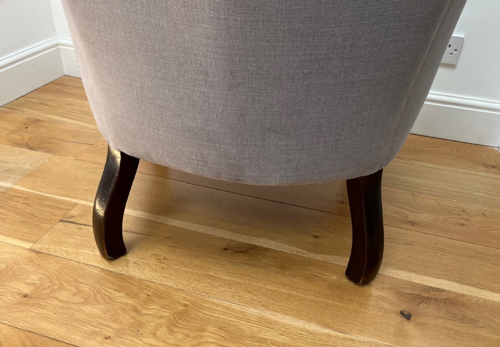 A high-backed Victorian barrel back armchair upholstered in light grey fabric, featuring channel-tufted back detailing and dark carved cabriole legs with ball and claw feet. View VI