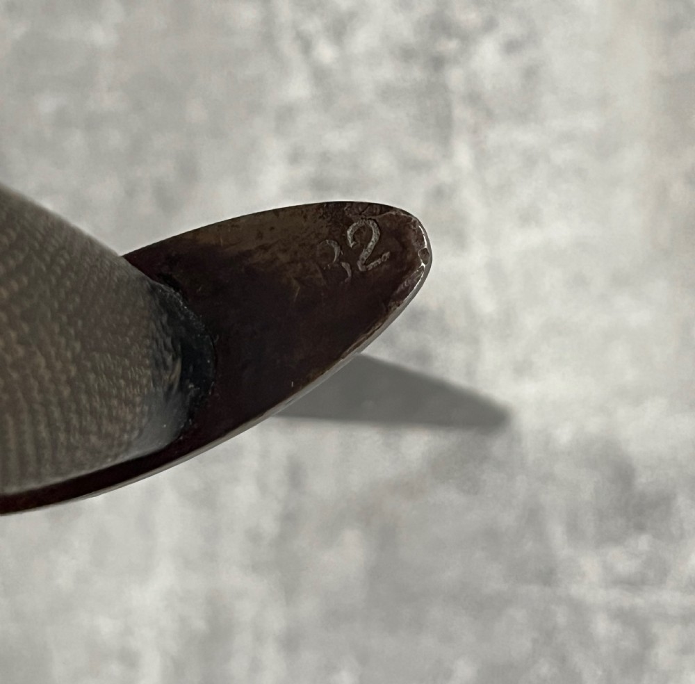 A Second World War Pattern 2 Fairbairn-Sykes combat dagger with a knurled grip resting next to its dark brown leather scabbard. View V