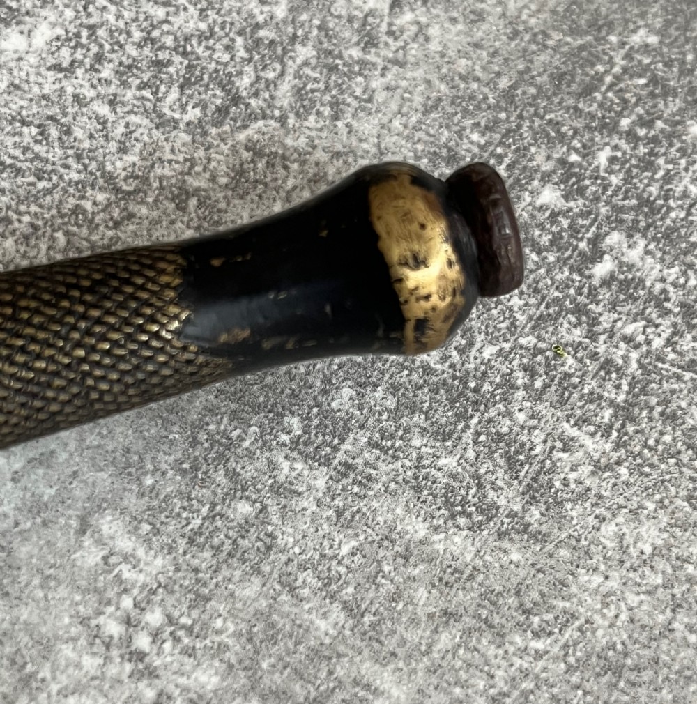 A Second World War Pattern 2 Fairbairn-Sykes combat dagger with a knurled grip resting next to its dark brown leather scabbard. View VII