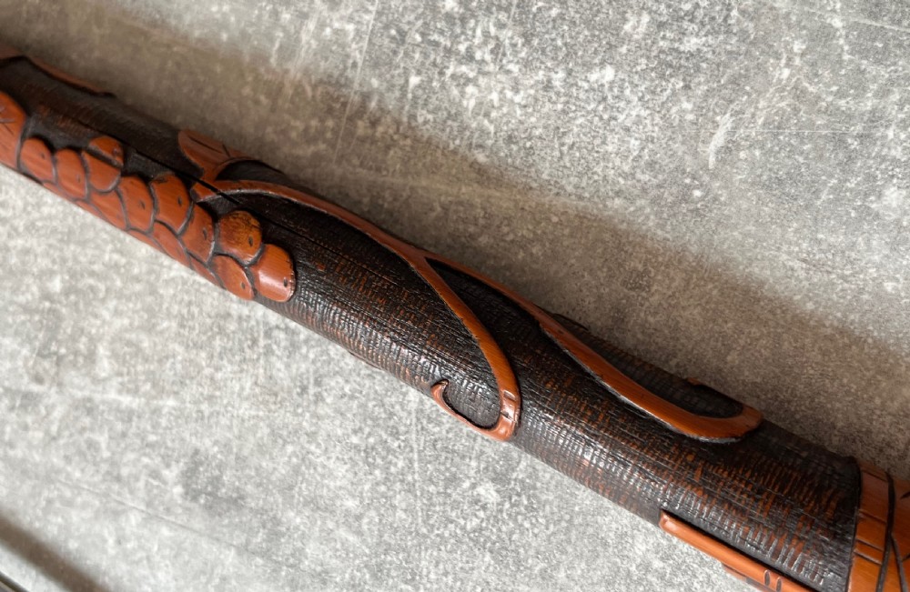 An antique East Asian carved bamboo sword stick shown unsheathed to reveal a long slender steel blade alongside its carved wooden shaft with brass fittings. View XII