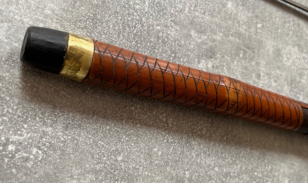 An antique East Asian carved bamboo sword stick shown unsheathed to reveal a long slender steel blade alongside its carved wooden shaft with brass fittings. View XIII