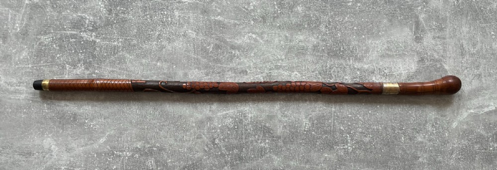 An antique East Asian carved bamboo sword stick shown unsheathed to reveal a long slender steel blade alongside its carved wooden shaft with brass fittings. View XV
