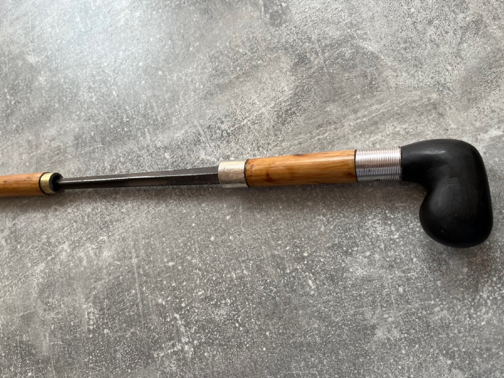 An antique bamboo walking stick shown disassembled to reveal a long steel blade and a dark curved pistol-grip handle with metal ferrules. View IV
