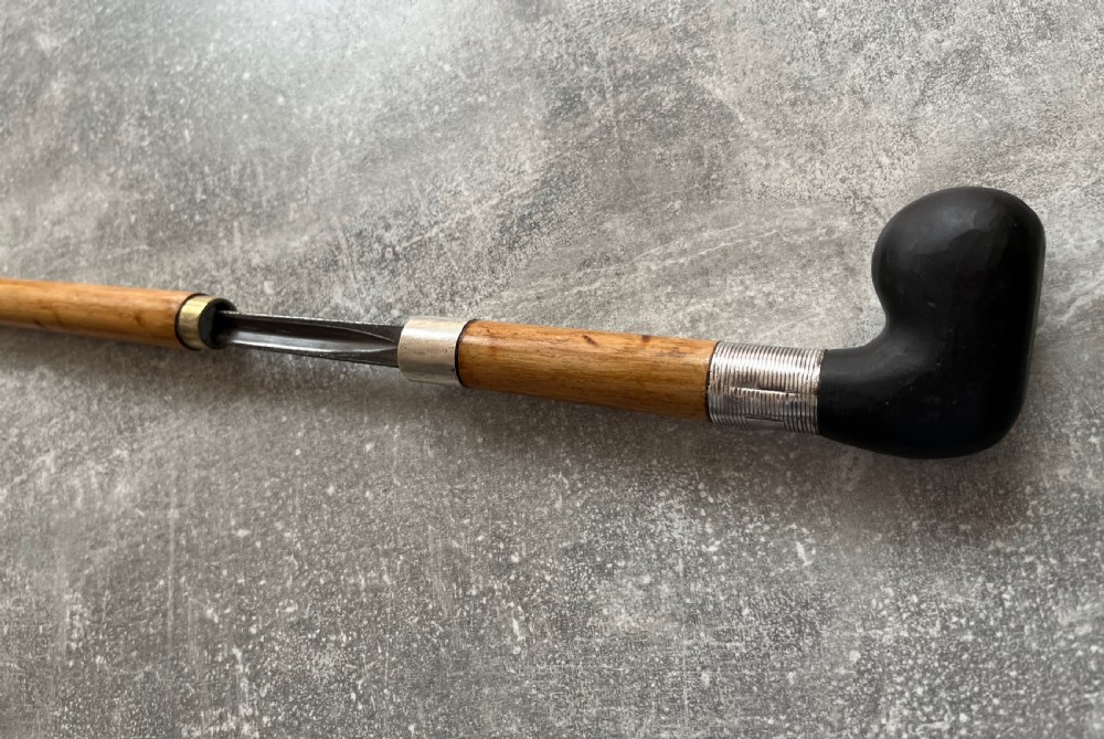 An antique bamboo walking stick shown disassembled to reveal a long steel blade and a dark curved pistol-grip handle with metal ferrules. View V