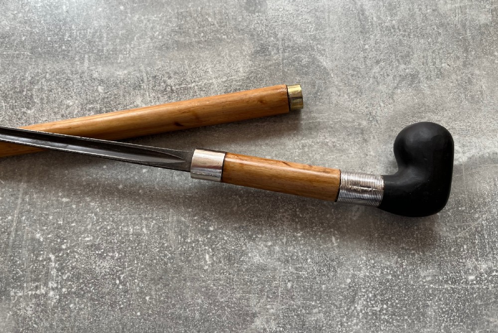 An antique bamboo walking stick shown disassembled to reveal a long steel blade and a dark curved pistol-grip handle with metal ferrules. View VI