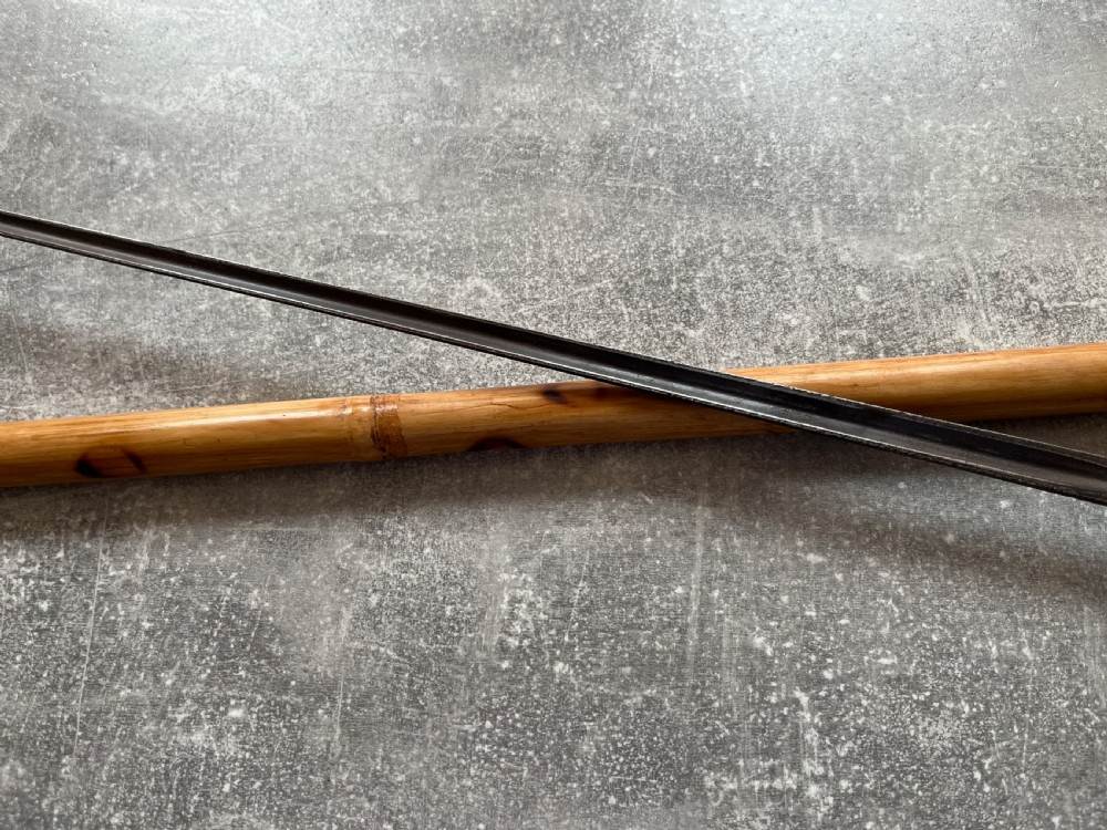 An antique bamboo walking stick shown disassembled to reveal a long steel blade and a dark curved pistol-grip handle with metal ferrules. View VII