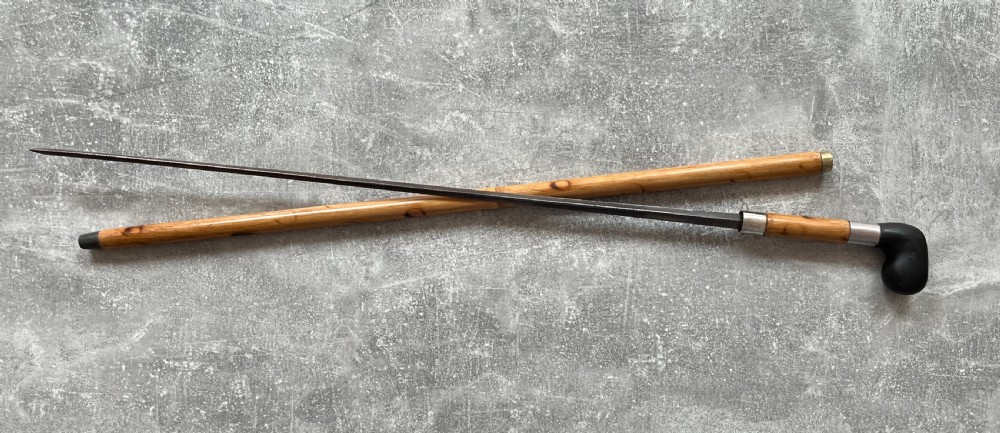 An antique bamboo walking stick shown disassembled to reveal a long steel blade and a dark curved pistol-grip handle with metal ferrules. View IX