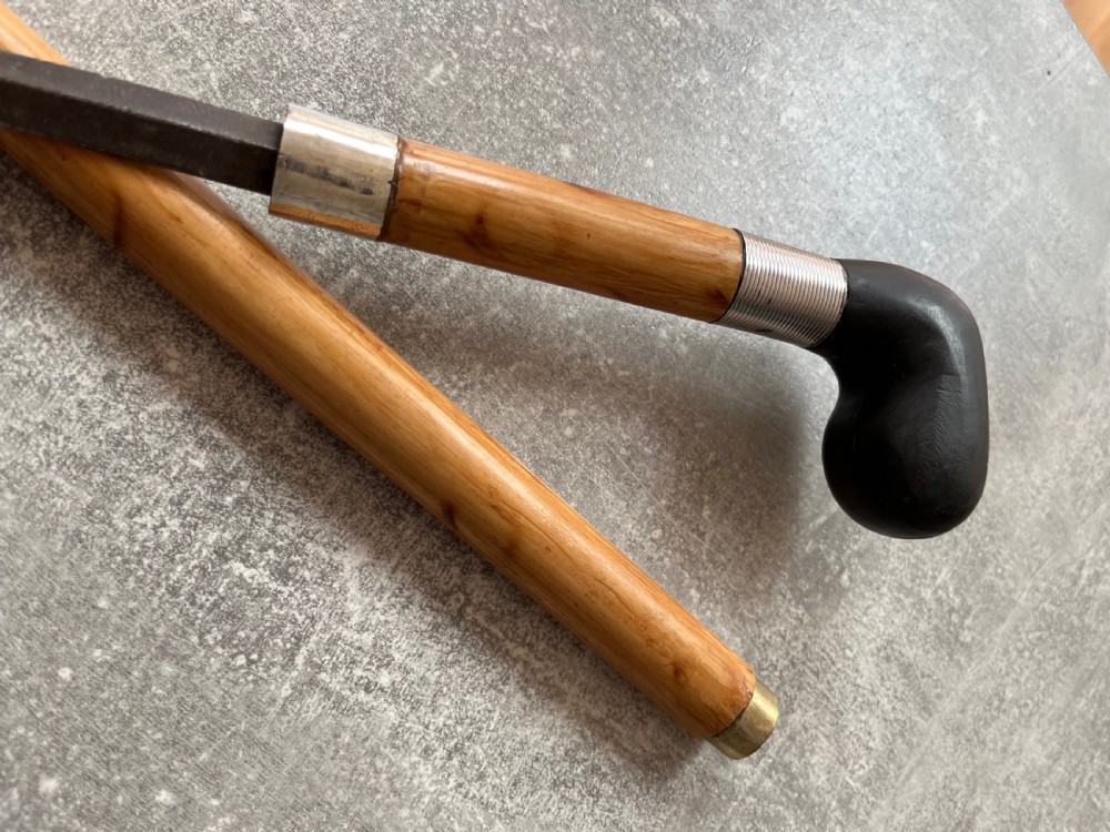 An antique bamboo walking stick shown disassembled to reveal a long steel blade and a dark curved pistol-grip handle with metal ferrules. View X
