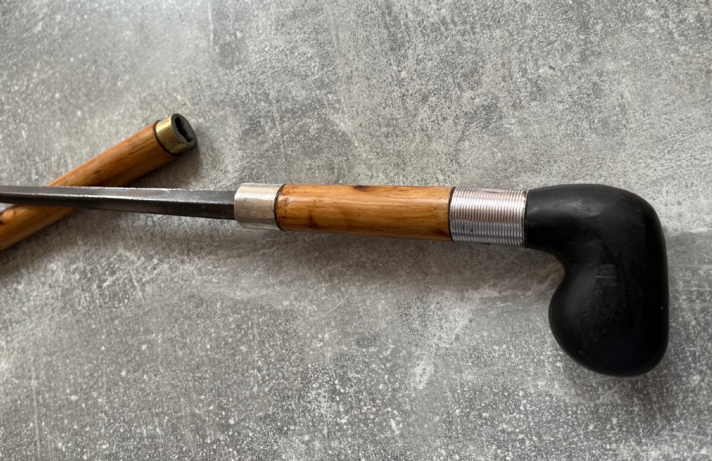 An antique bamboo walking stick shown disassembled to reveal a long steel blade and a dark curved pistol-grip handle with metal ferrules. View XI