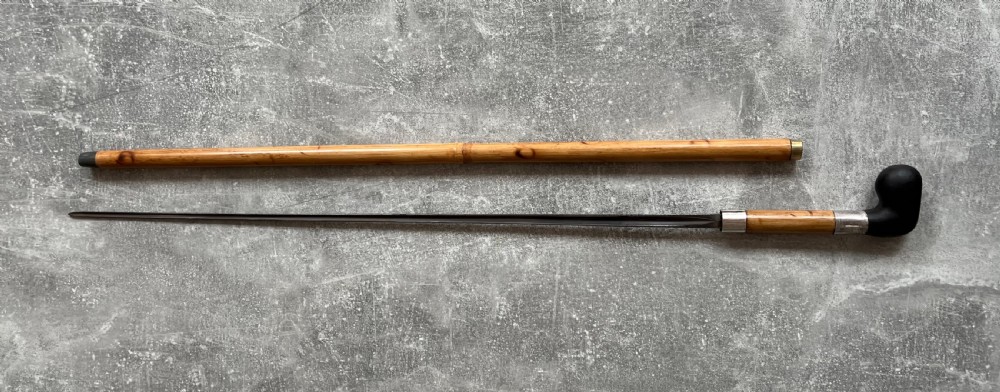 An antique bamboo walking stick shown disassembled to reveal a long steel blade and a dark curved pistol-grip handle with metal ferrules. View XII