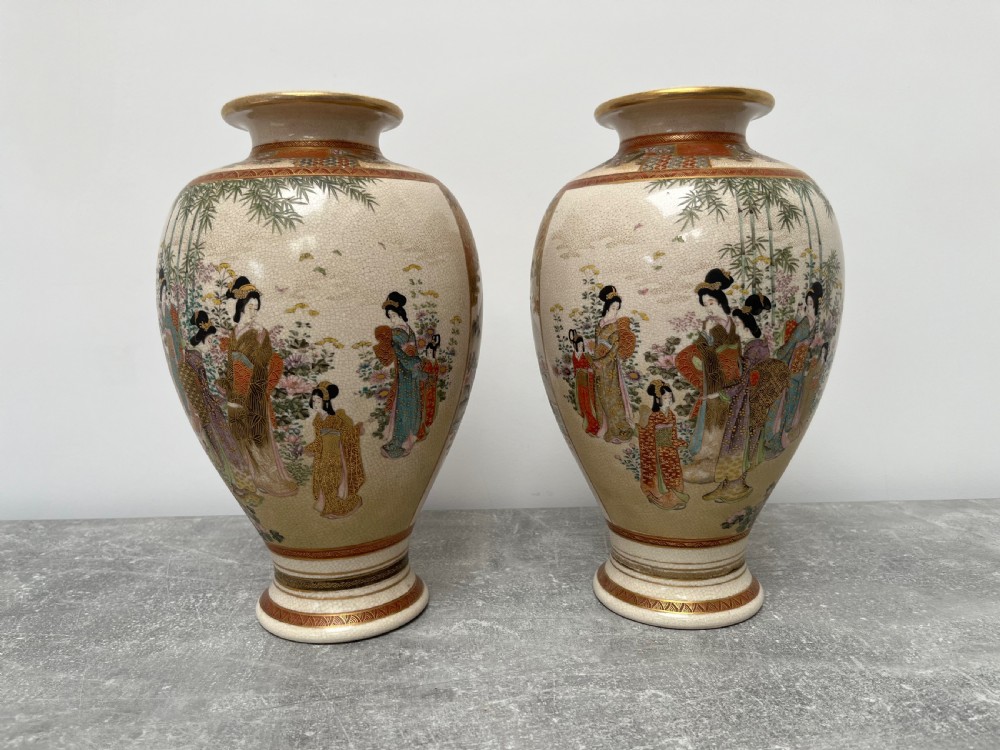 A pair of baluster-shaped Japanese Satsuma earthenware vases decorated with painted figures in landscapes under a crackled cream glaze with gilded borders. View II