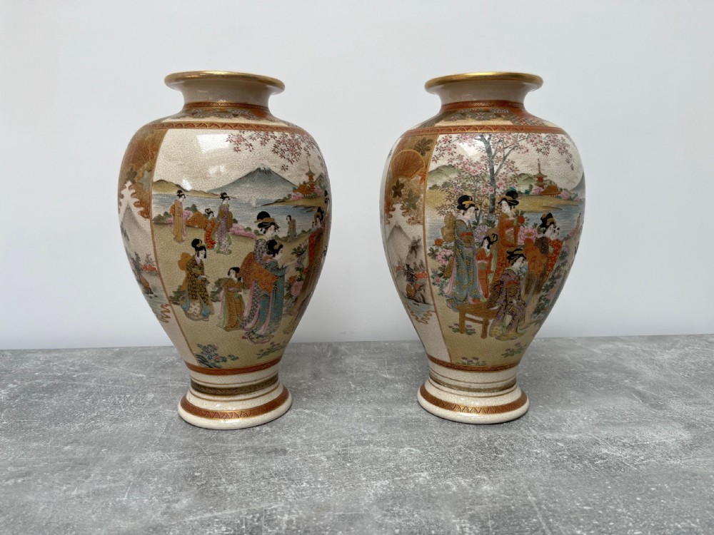 A pair of baluster-shaped Japanese Satsuma earthenware vases decorated with painted figures in landscapes under a crackled cream glaze with gilded borders. View V