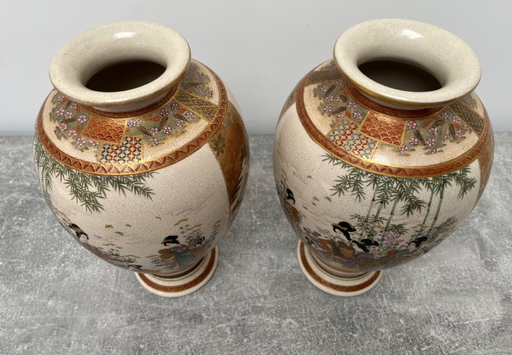 A pair of baluster-shaped Japanese Satsuma earthenware vases decorated with painted figures in landscapes under a crackled cream glaze with gilded borders. View VII