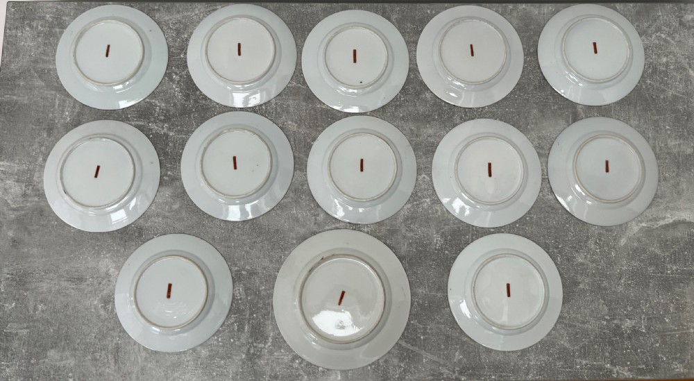A set of twelve circular Japanese Satsuma earthenware plates featuring hand-painted landscape scenes with figures framed by wide gilded decorative borders. View VI