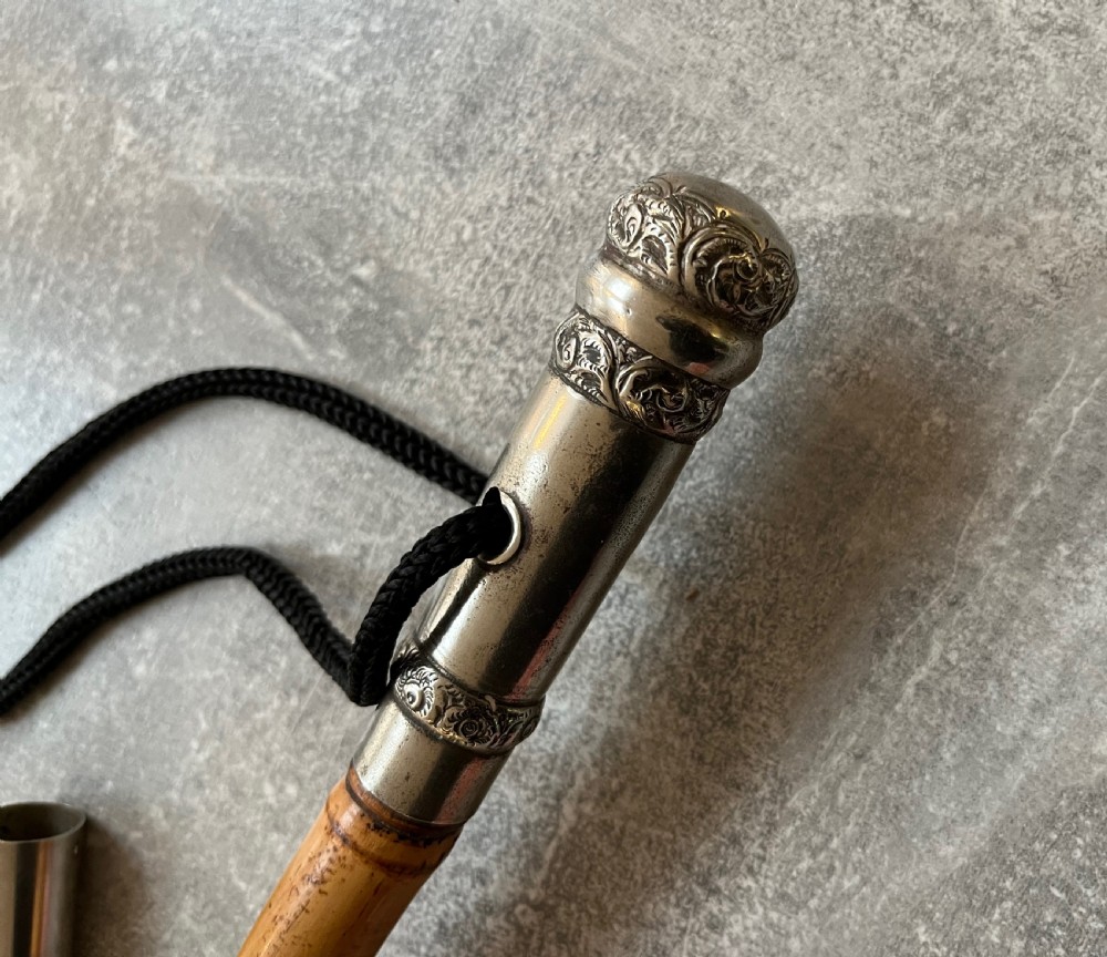 An early twentieth-century bamboo sword stick featuring an embossed silver pommel, a narrow steel blade, and a woven black wrist cord. View V