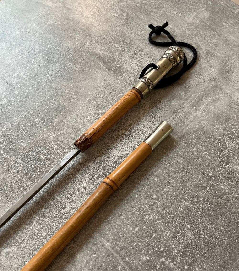 An early twentieth-century bamboo sword stick featuring an embossed silver pommel, a narrow steel blade, and a woven black wrist cord. View VIII