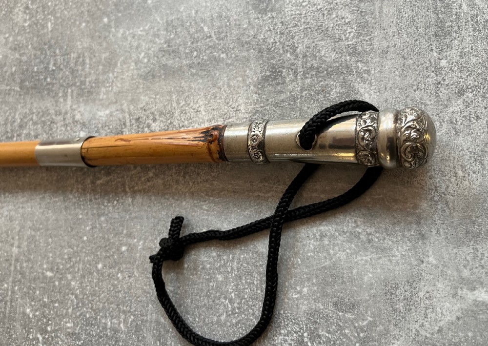 An early twentieth-century bamboo sword stick featuring an embossed silver pommel, a narrow steel blade, and a woven black wrist cord. View X
