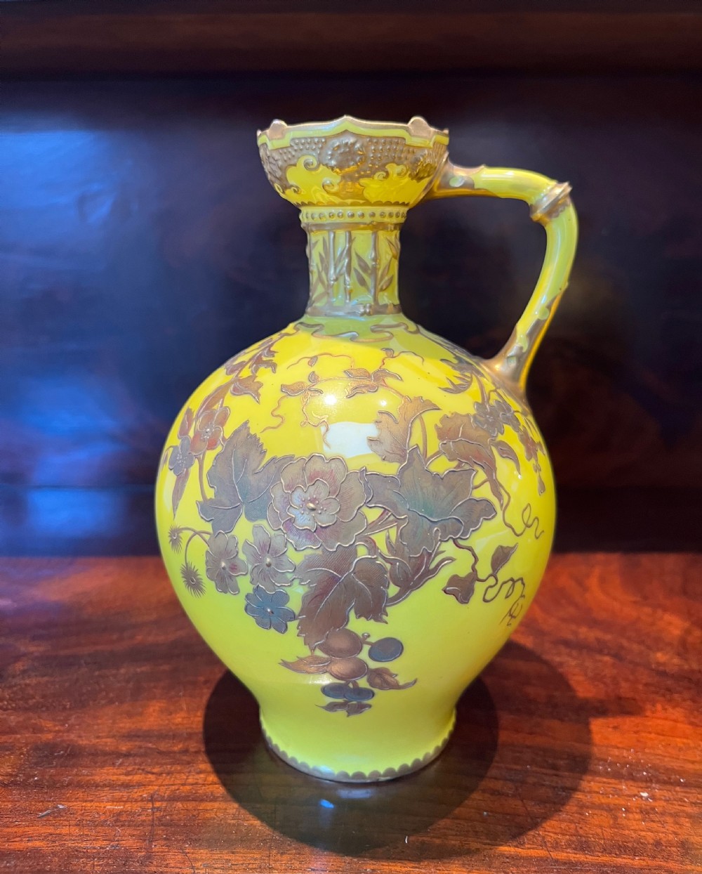 A pair of yellow porcelain ewers with gilded floral decoration, narrow necks, and single handles. View V