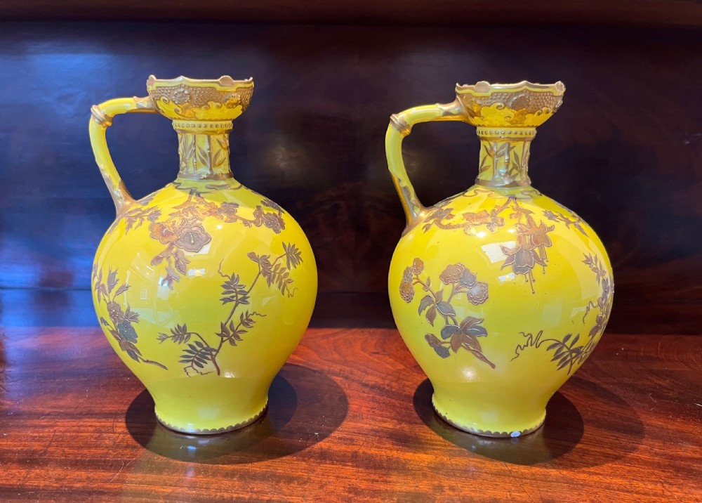 A pair of yellow porcelain ewers with gilded floral decoration, narrow necks, and single handles. View IX