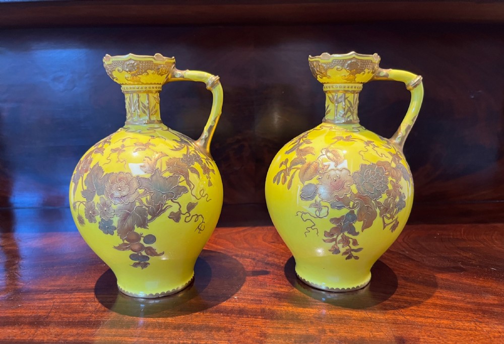 A pair of yellow porcelain ewers with gilded floral decoration, narrow necks, and single handles. View X