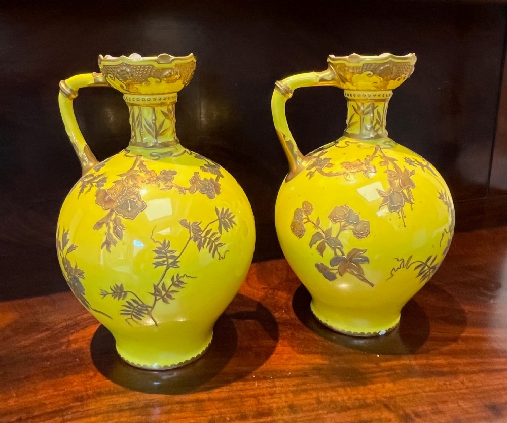 A pair of yellow porcelain ewers with gilded floral decoration, narrow necks, and single handles. View XV