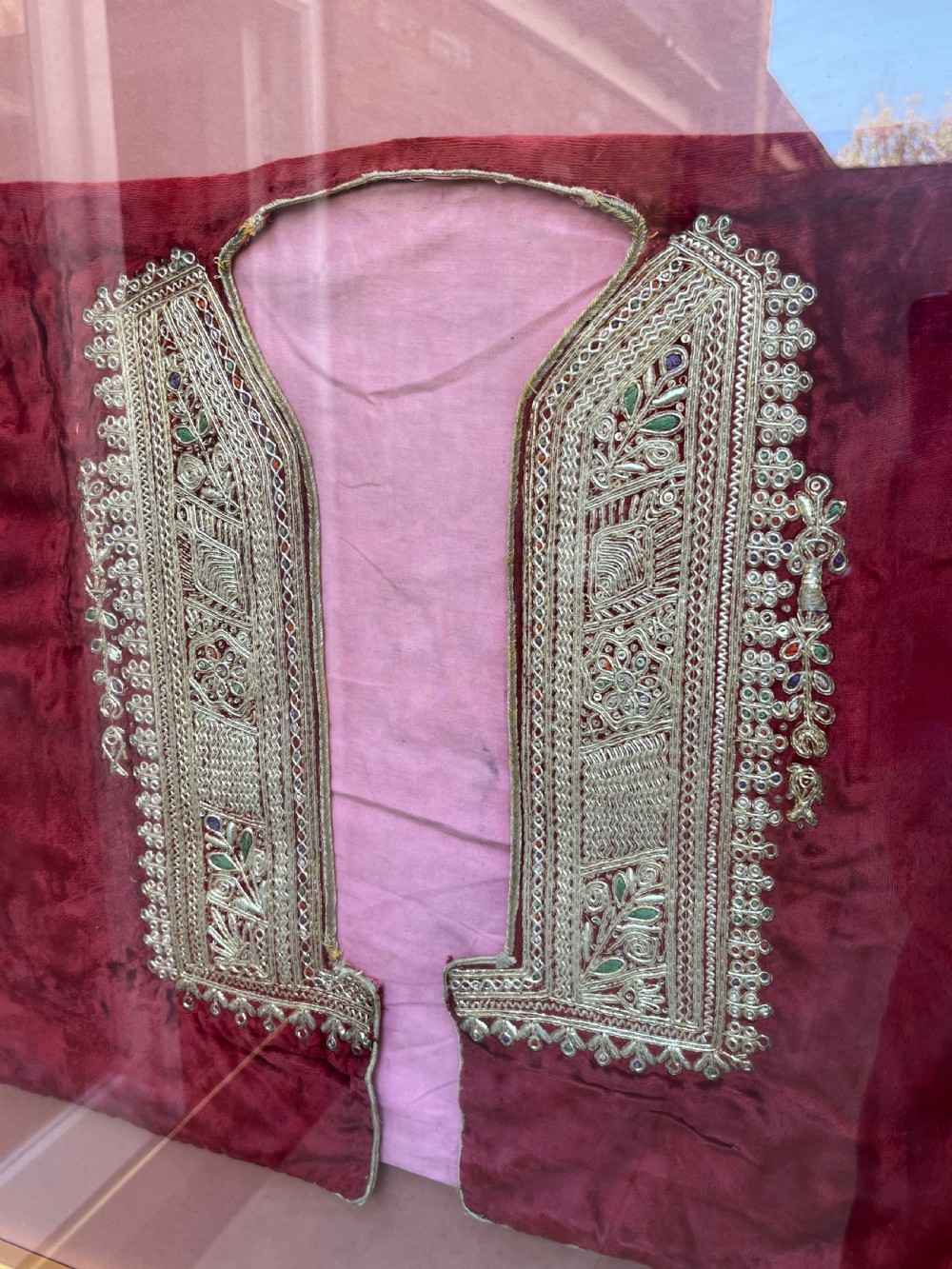 A late 19th-century Ottoman red velvet and purple silk jacket with heavy gold metallic embroidery, presented inside a thin gold wood frame. View II