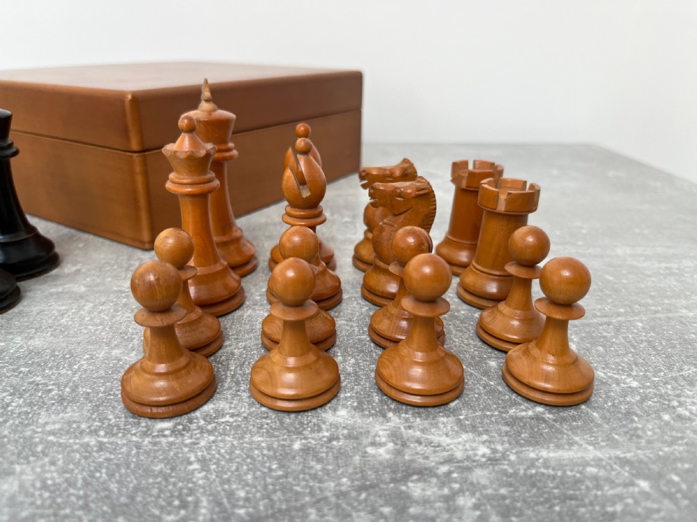 A wooden folding chess board featuring geometric inlaid borders and a full set of light and dark Staunton style chess pieces. View V