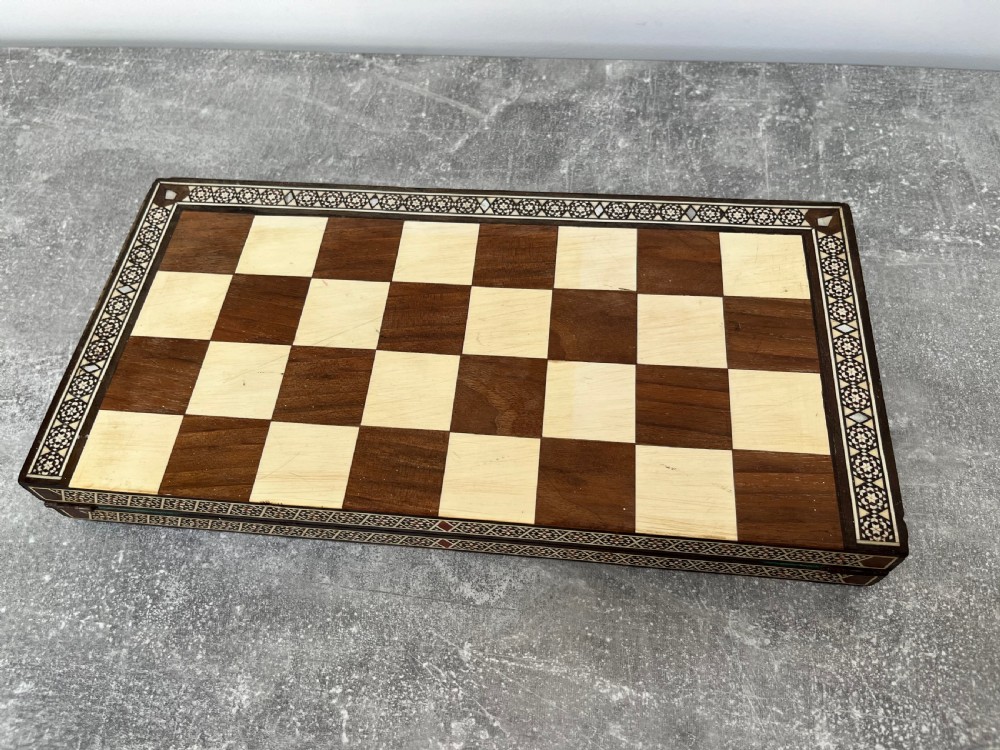 A wooden folding chess board featuring geometric inlaid borders and a full set of light and dark Staunton style chess pieces. View VIII
