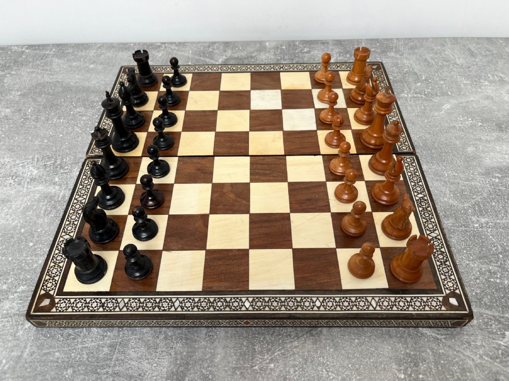 A wooden folding chess board featuring geometric inlaid borders and a full set of light and dark Staunton style chess pieces. View XV