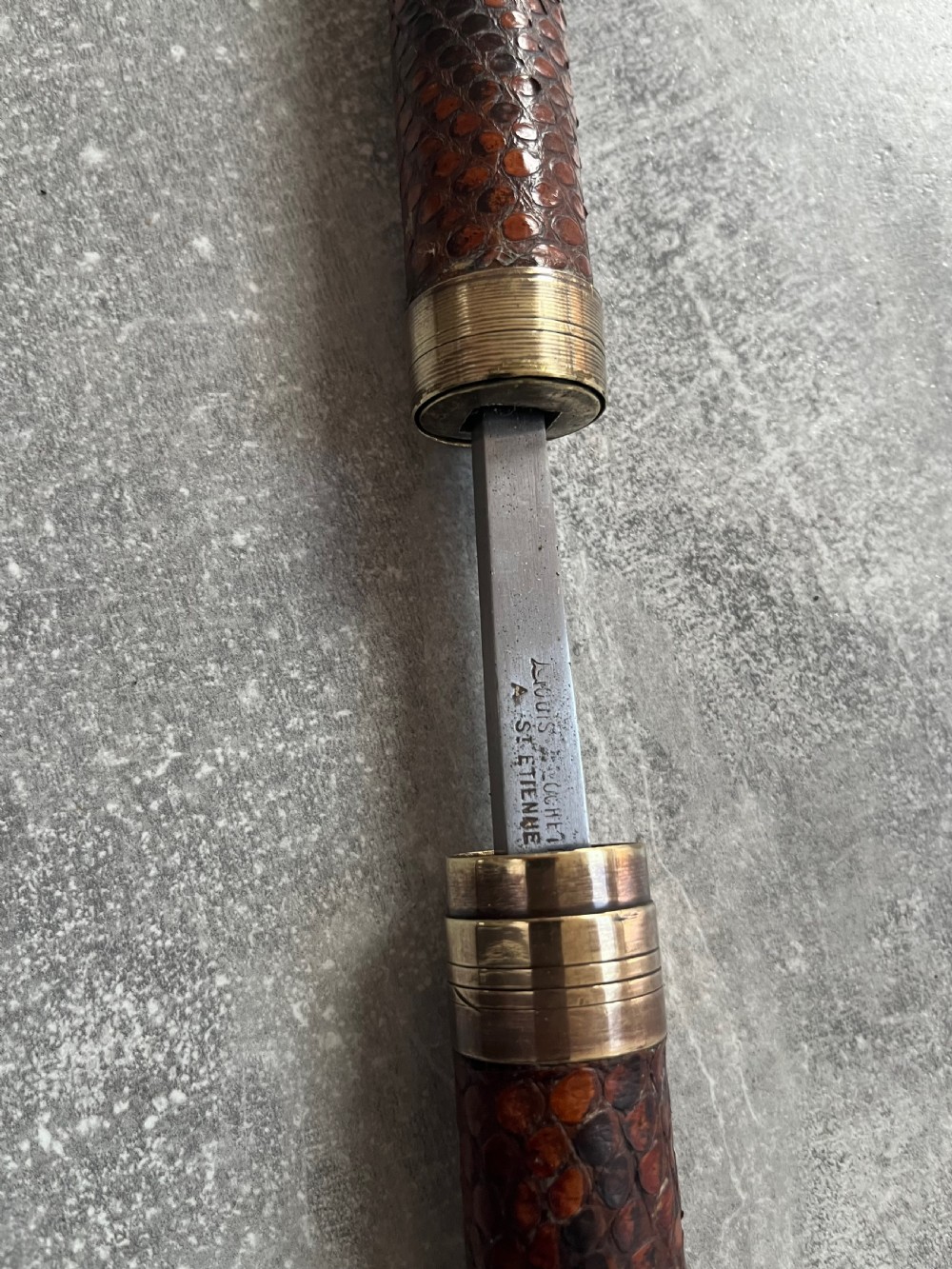 An antique French sword stick with a curved antler handle, brass collars, a narrow steel blade, and a sheath wrapped in dark brown snakeskin. View VIII