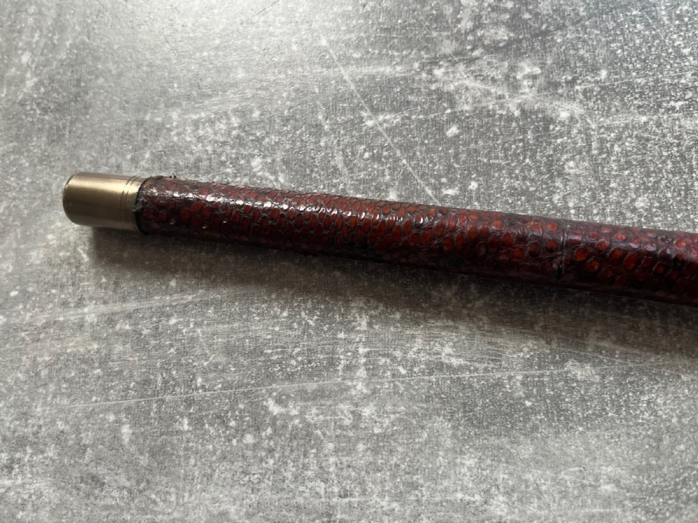 An antique French sword stick with a curved antler handle, brass collars, a narrow steel blade, and a sheath wrapped in dark brown snakeskin. View XIII