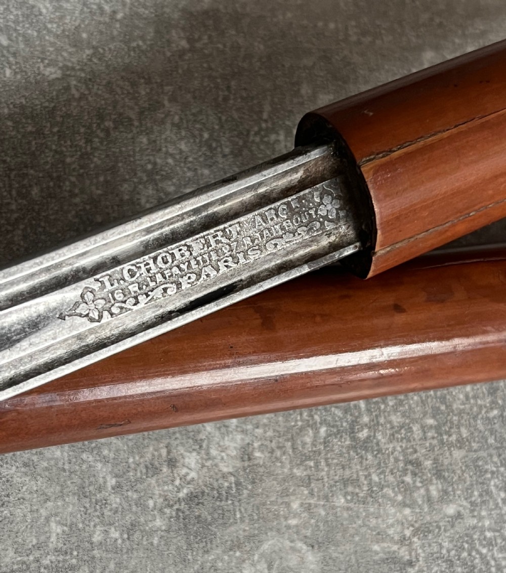 An antique French sword stick featuring an L-shaped horn handle, a gold-coloured engraved collar, a dark wooden sheath, and a slender unsheathed steel blade. View III