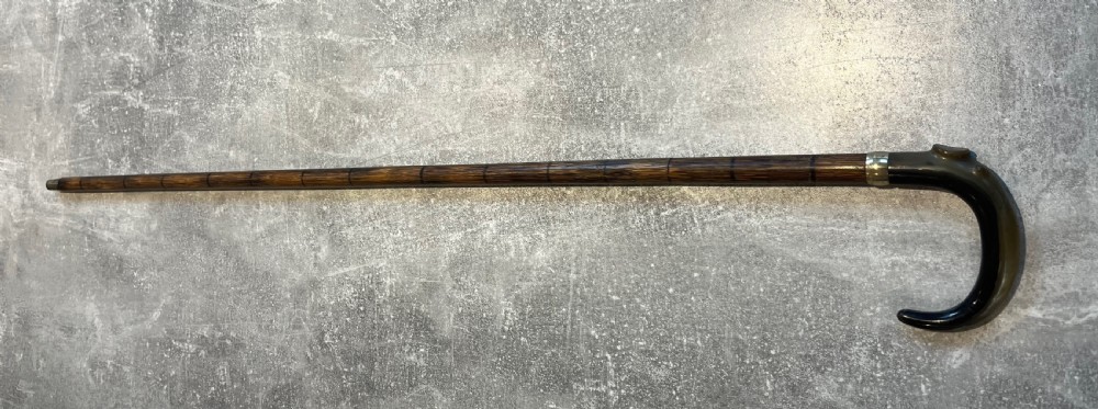 An antique Malacca walking stick unsheathed to reveal a long narrow steel sword blade, featuring a curved dark horn crook handle with a metal collar. View XIV