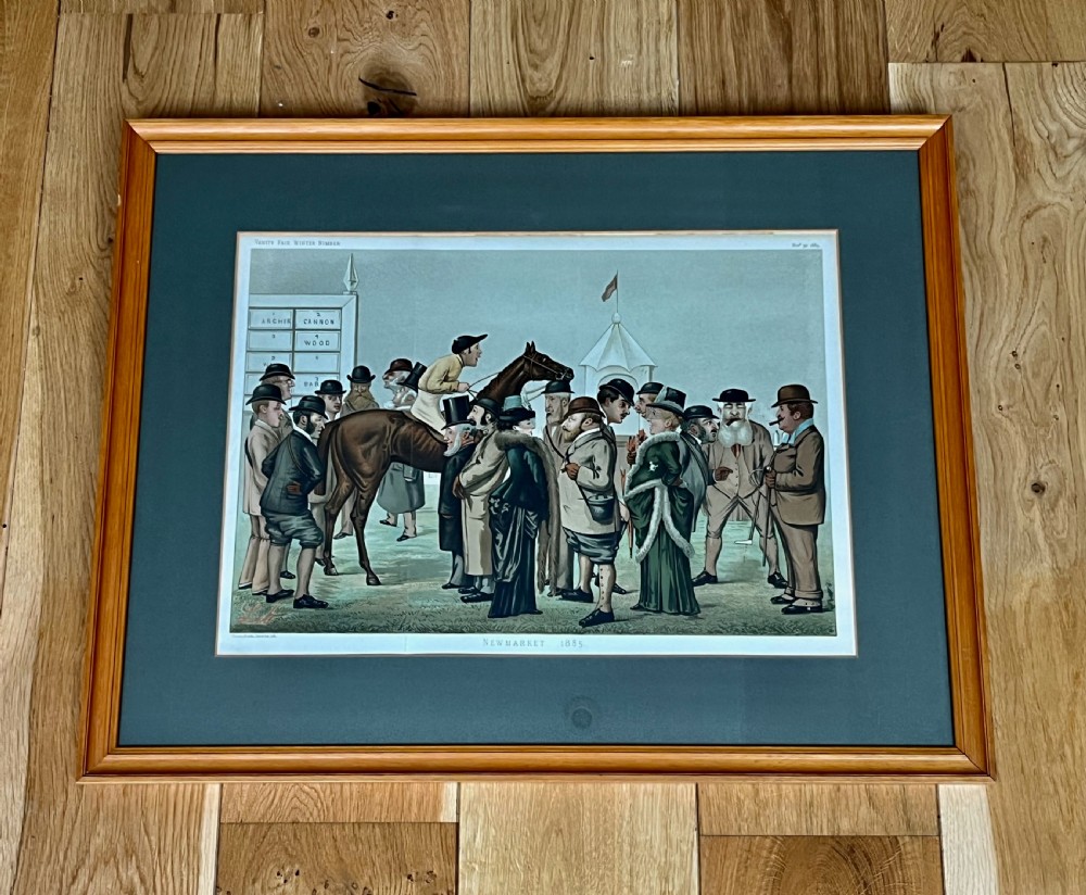 A Victorian framed Vanity Fair chromolithograph print titled Newmarket 1885 depicting an equestrian caricature scene inside a dark green mount and light wood frame.