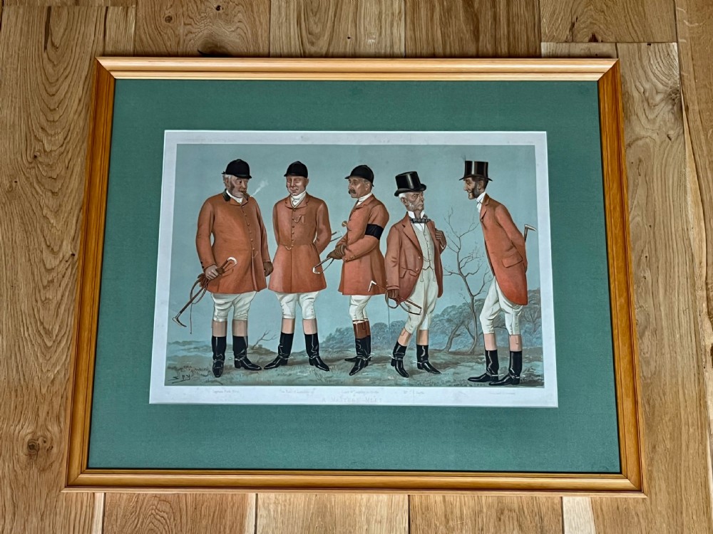 A framed Vanity Fair colour lithograph depicting five gentlemen in traditional red hunting attire set against a blue backdrop within a green card mount and simple wooden frame.