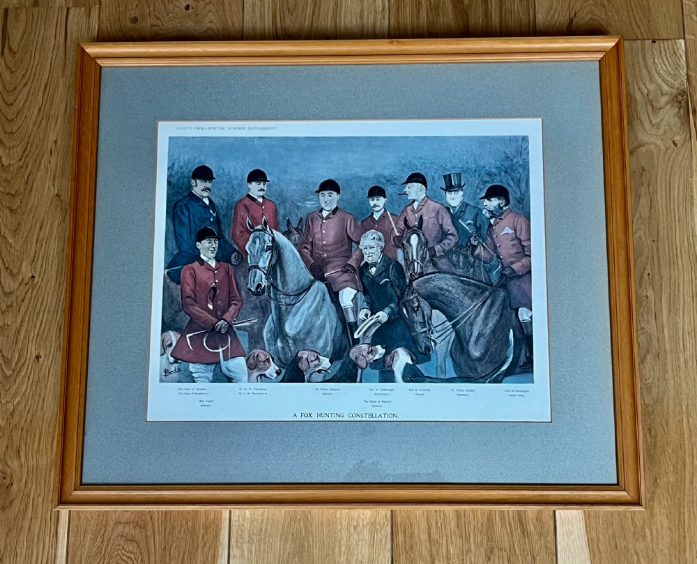 A framed Vanity Fair colour lithograph depicting five gentlemen in traditional red hunting attire set against a blue backdrop within a green card mount and simple wooden frame. View VII