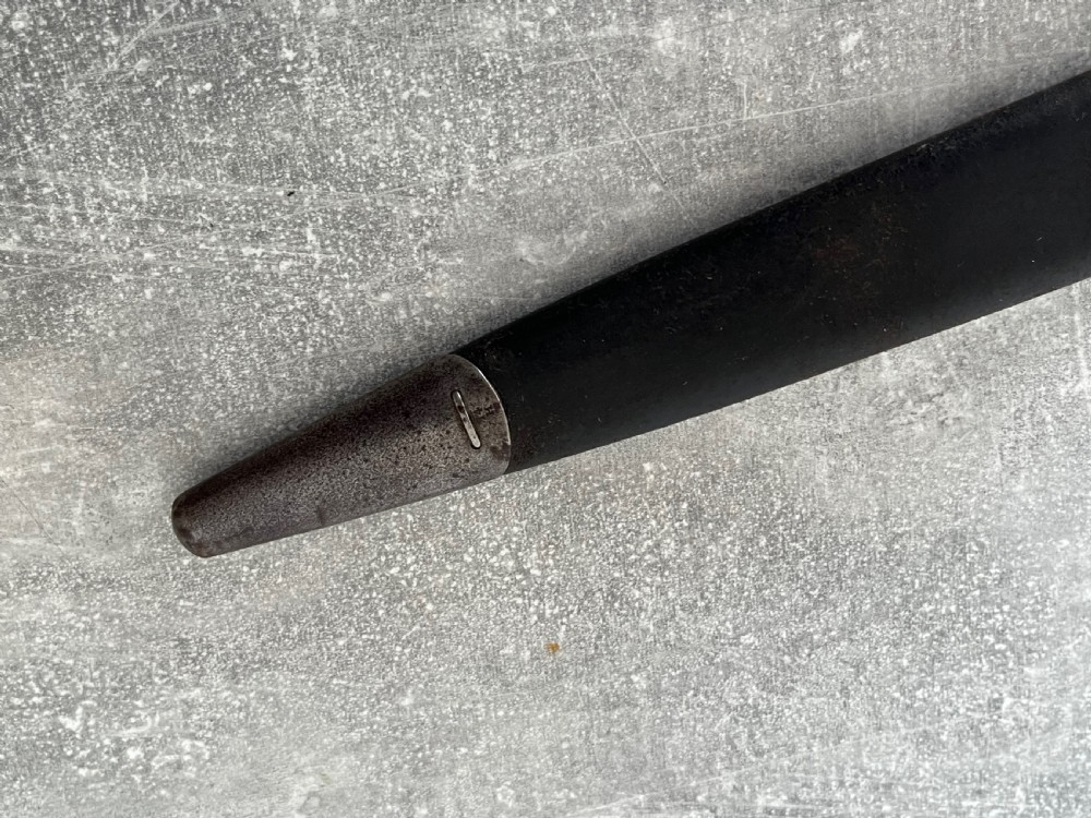 A Victorian British Pattern 1888 Mark 1 Type 2 sword bayonet with a double-edged steel blade, wooden handle grips secured with brass rivets, alongside its dark leather and steel-mounted scabbard. View XII